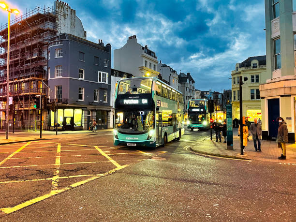 brighton, united kingdom - march 04 2022: a public british bus is driving at night over a crossing with crosses on it in a city
