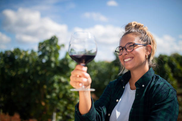 улыбающаяся женщина-винодел держит бокал вина в винограднике - red grape grape fruit sweet food стоковые фото и изображения