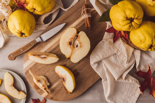 ripe whole and sliced quinces. fresh fruit for preparing recipes with cinnamon and lemon. an essential ingredient for a healthy diet - quince imagens e fotografias de stock