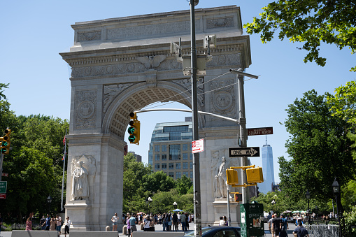 New York, NY, USA - June 4, 2022: The north face of the Washington Square Arch in Washington Square Park. One World Trade Center can be seen in the background.