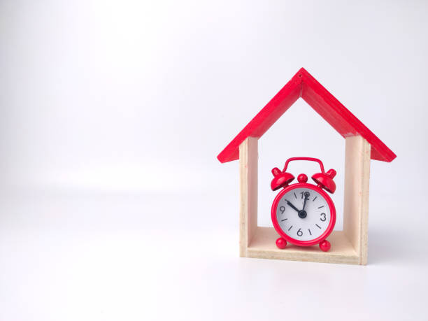 istock Alarm clock and toy house on a white background with copy space. 1431523635