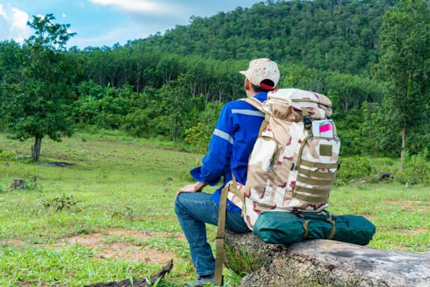istock A young tourist with a backpack and a tent sits on a log, looking at the high mountains. 1431540990