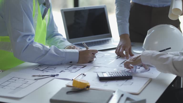 Engineers and architects meet to place construction work with blueprints on the table.