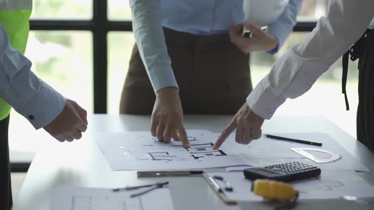 Engineers and architects meet to place construction work with blueprints on the table.