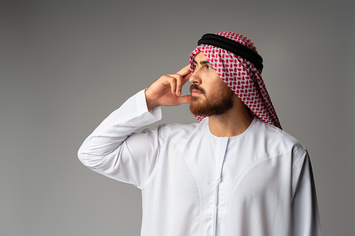Joven árabe vestido con ropa tradicional pensando en algo photo