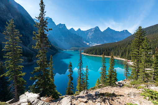 Moraine lake beautiful landscape in summer sunny day morning. Shadow moves on turquoise blue water with reflection. Canadian Rockies. Banff National Park. Alberta, Canada.