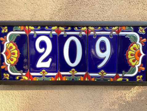 Ceramic Number 209 Street Address; Colorful Mexican floral tiles on adobe wall. Shot in Santa Fe, NM.
