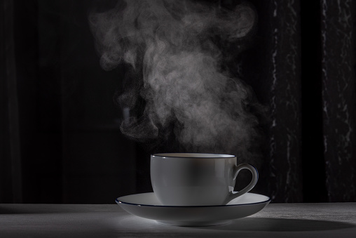 A cup of coffee on the table with rising steam. Copy space.