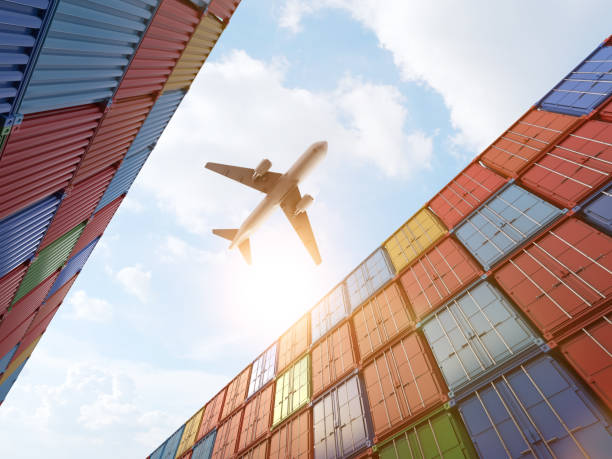 Cargo plane flying above stack of containers at container port stock photo