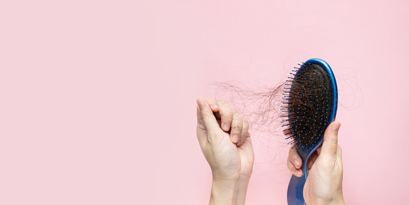 woman hand is removing hair from blue brush. A Hair care.