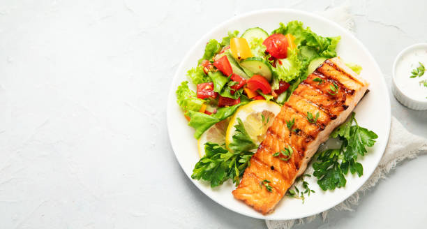 istock Salmon steak with vegetables and fries on light background. 1431581510