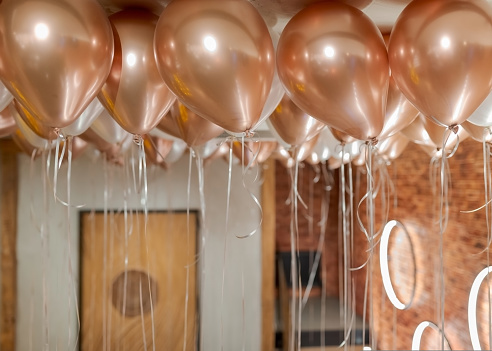 Colourful helium brown balloons with tails flying under ceiling decoration.