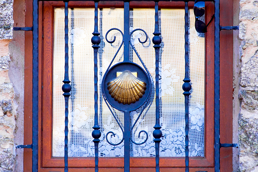 Cast iron railing detail and  scallop carving, stone house window, Camino de Santiago symbol. Ancient pilgrimage route, UNESCO world heritage.