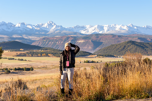 A woman tourist admiring a beautiful morning view of snow covered Sneffels Range with blue sky near Ridgway, Colorado, USA.