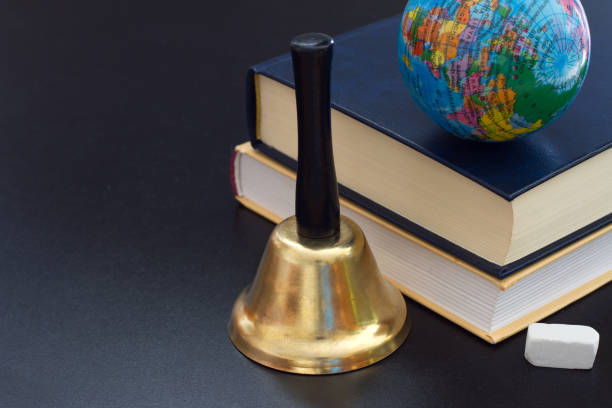 istock Bell, books and globe on blackboard, back to school concept 1431597676