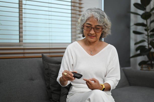 Senior diabetic woman using glucose meter checking blood sugar level at home. Diabetes, health care concept. Senior diabetic woman using glucose meter checking blood sugar level at home. Diabetes, health care concept. diabetes stock pictures, royalty-free photos & images