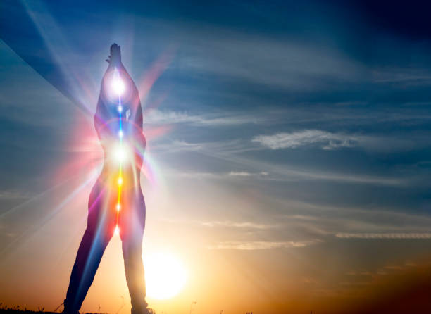 Silhouette of woman in yoga pose on beach sunset view, glowing s stock photo