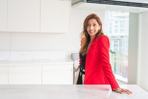 Portrait of beautiful businesswoman in office wearing red suit jacket and smiling