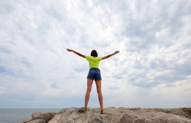 mädchen führt gymnastikübungen auf den felsen am meer durch, ohne ihr gesicht zu zeigen - 16199 stock-fotos und bilder