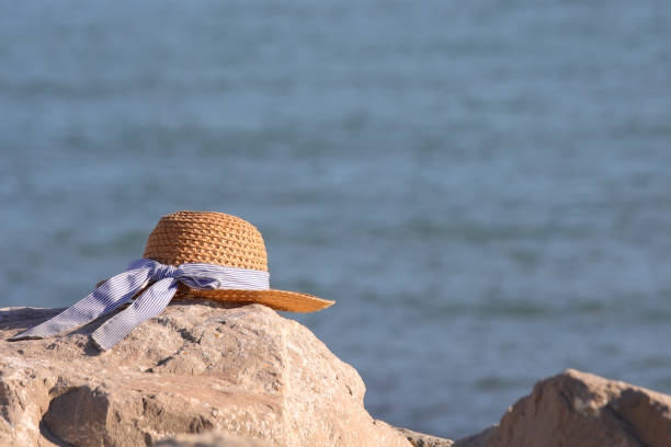 straw hat on the rocks by the sea and space for a custom text to be placed above