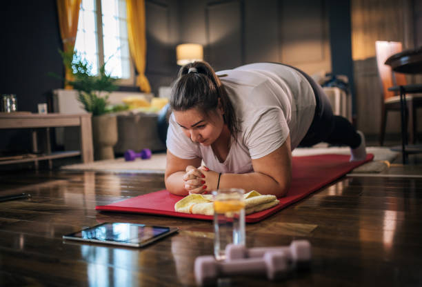 istock plus size woman following workout video on laptop and doing home workout 1431610964