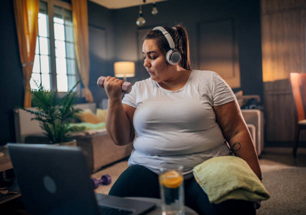 istock plus size woman following workout video on laptop and doing home workout 1431611166