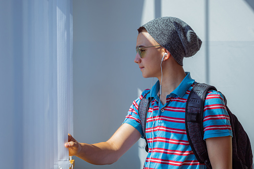 A side view of a student with a style standing by the window in the classroom. Ready for school concept.