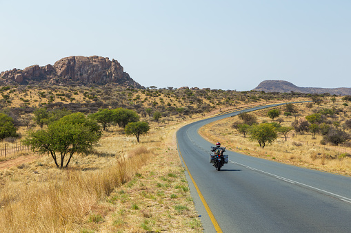 Khomas, Namibia - 28 September 2018: Motorcycle on the road. Namibian landscape along the highway.Hills and African vegetation around.