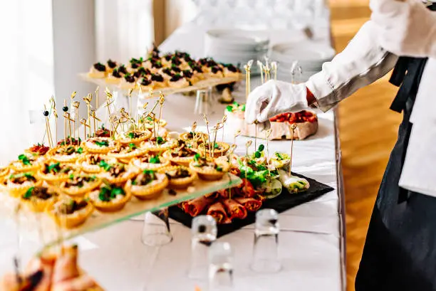 Photo of woman hands of a waiter prepare food for a buffet table in a restaurant