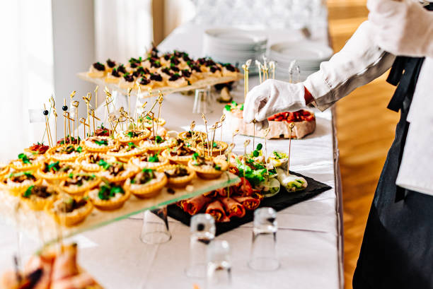 mãos mulheres de um garçom preparar comida para uma mesa de buffet em um restaurante - buffet - fotografias e filmes do acervo