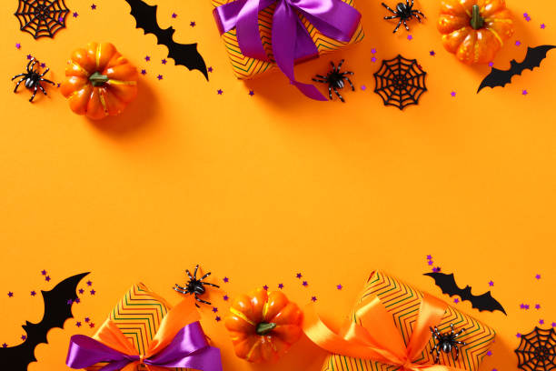 istock Modern Halloween background. Frame made of Halloween decorations, pumpkins, gift boxes, spiders, bats, webs on orange table. Flat lay, top view. 1431623970