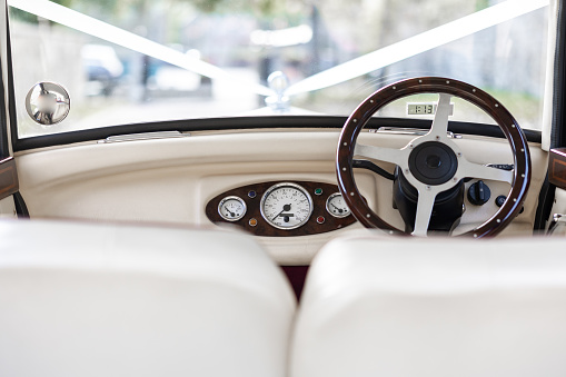 Classic retro vintage wedding car in white, 90 year old with dashboard and steering wheel.