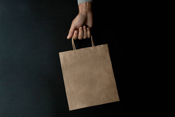 hand carrying a kraft zero waste shopping bag, environmental care stock photo