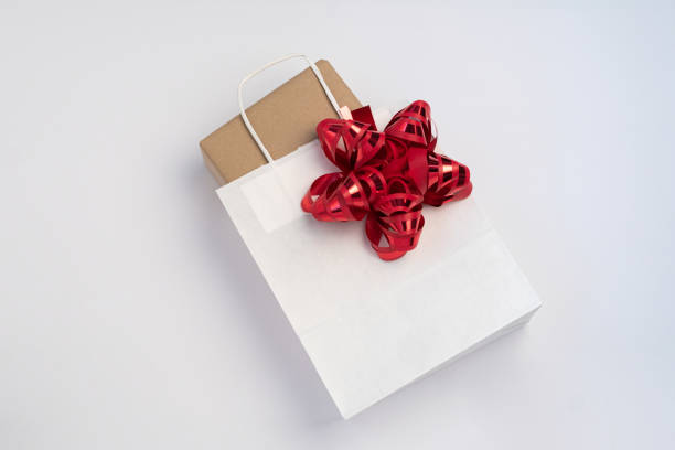 Present box in a clean white paper bag with red bow stock photo