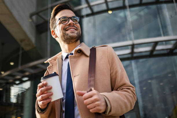 Young businessman walking drinking coffee