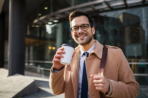 Handsome young businessman walking drinking coffee
