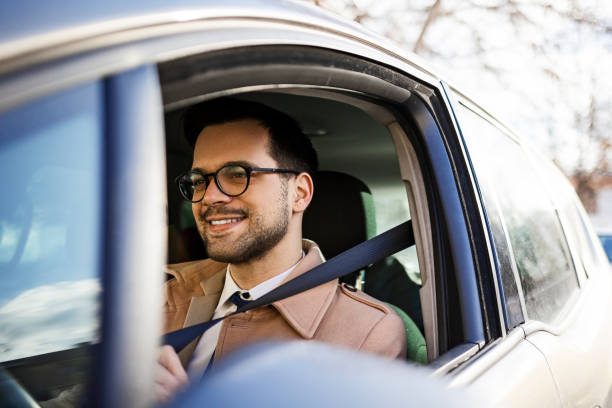 бизнесмен пристегивает ремень безопасности в своем автомобиле - seat belt safety protection driving стоковые фото и изображения