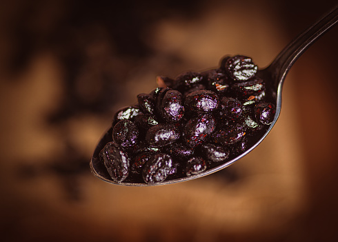 close-up of a metal spoon with coffee beans, freshly roasted, with copy space