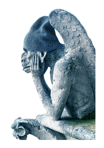 Gargoyle feeling cold isolated on white background, Paris, France. Funny gargoyle (chimera) statue in winter knitted hat. Concept of expensive gas and electricity, energy crisis, travel and weather.