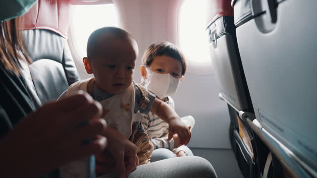 Asian parent with two sons traveling by commercial plane