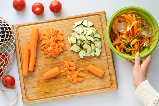 Woman chopping vegetables and making compost from peelings - table top view