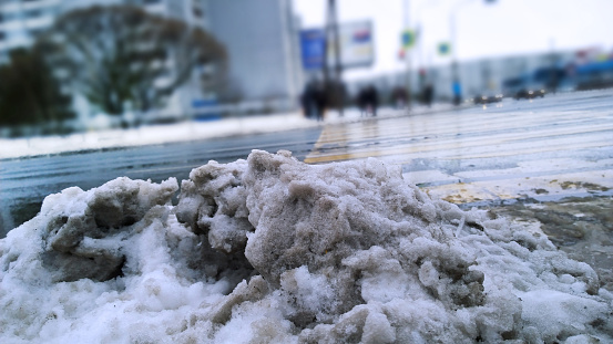 Pile of dirty melted snow on road. Winter is here. Frosty Cold weather. Snowfall in city. Problem of street snow removal. Messy. Chilly. Cityscape. Blurred background. Salt. Ecology concept. Town.