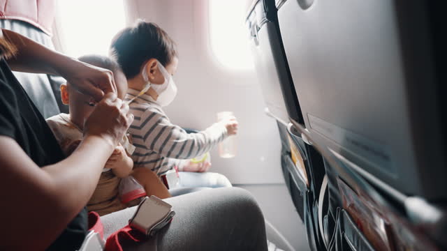 Asian mother with two sons traveling by commercial plane