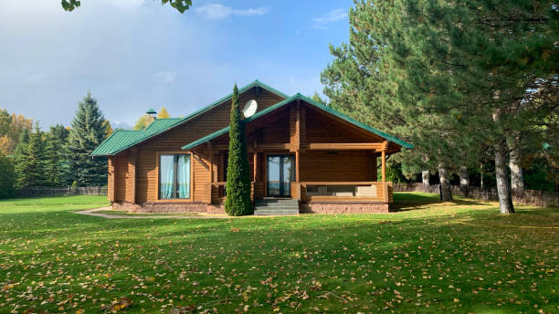 chalet moderne avec pelouse ith feuilles colorées dessus dans une journée d’automne ensoleillée - cottage autumn wood woods photos et images de collection