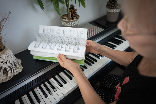 Close up elderly women looking musical note book at home