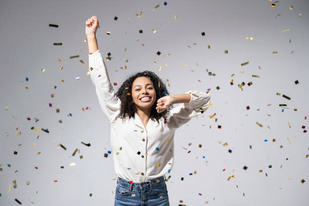 istock Joyful woman laughing, dancing and has fun with falling confetti. Enjoying life, celebration concepts 1431664126