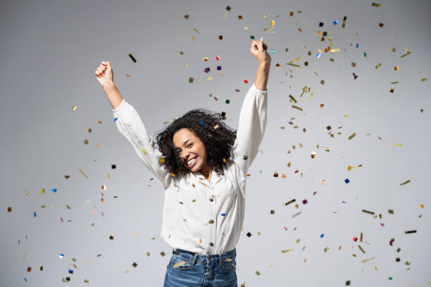 istock Joyful woman laughing, dancing and has fun with falling confetti. Enjoying life, celebration concepts 1431664295