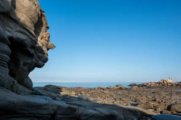 Photo of Man shaped rock and reefs by the sea