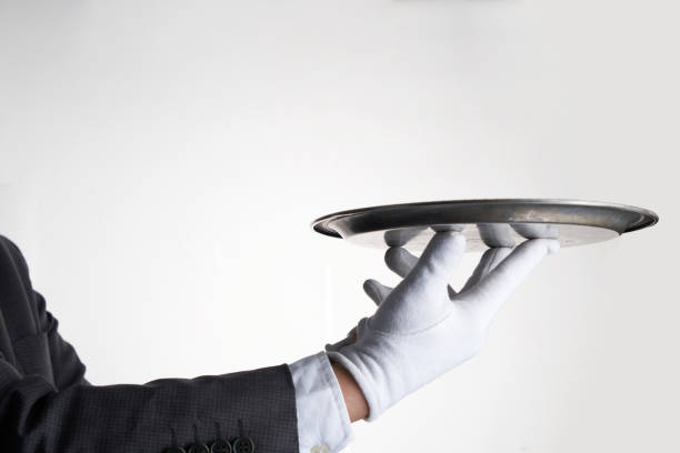 istock Elegant waiter hand in white glove holding an empty plate with white background. 1431685292