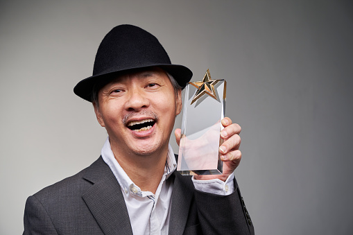 businessman holding crystal star trophy against gray background